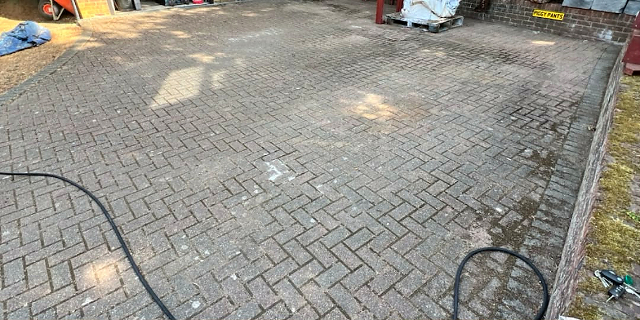 Herringbone block paved garage forecourt cleaned — before