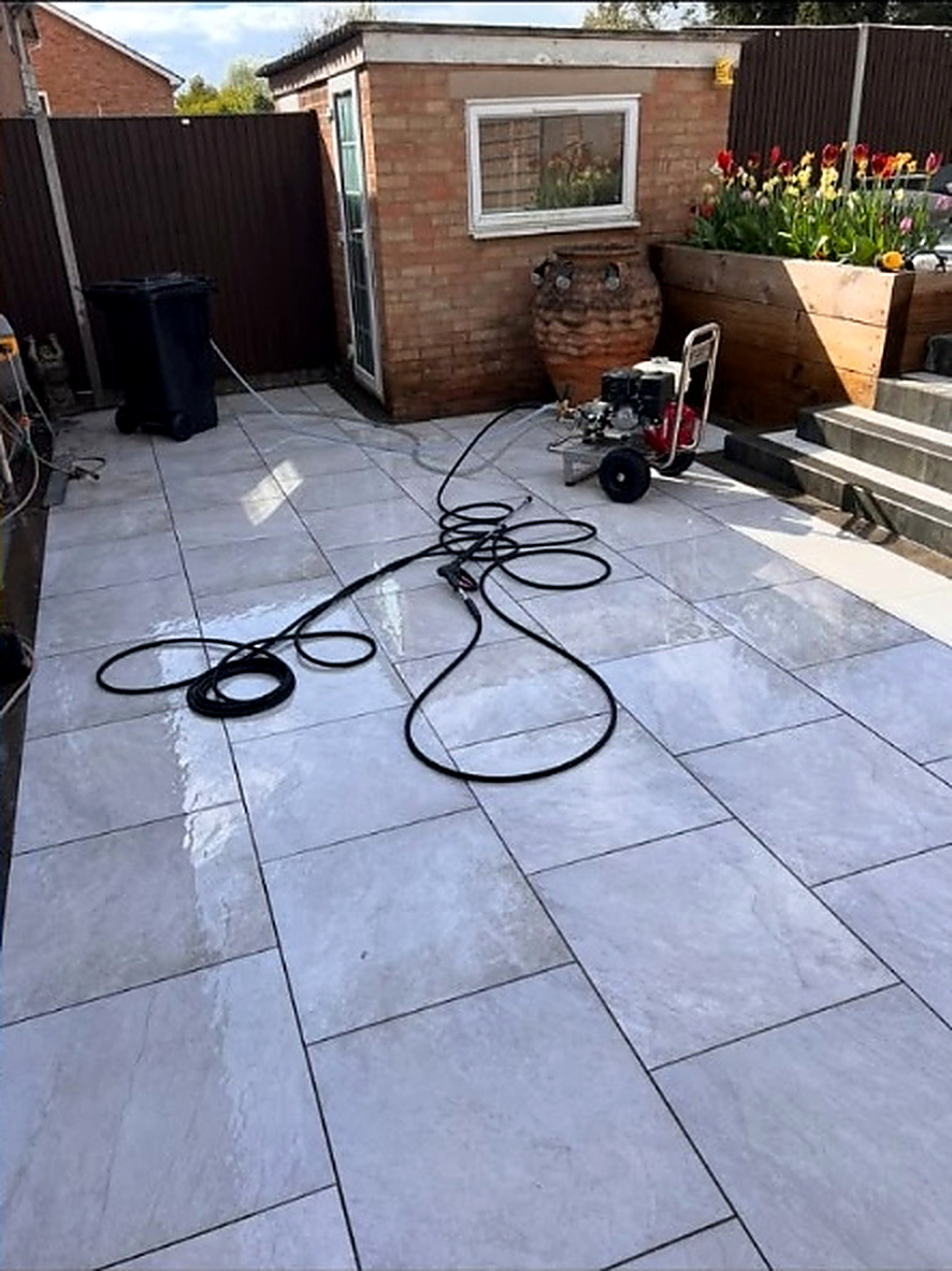 Green algae-covered porcelain patio cleaned back to a bright finish — after