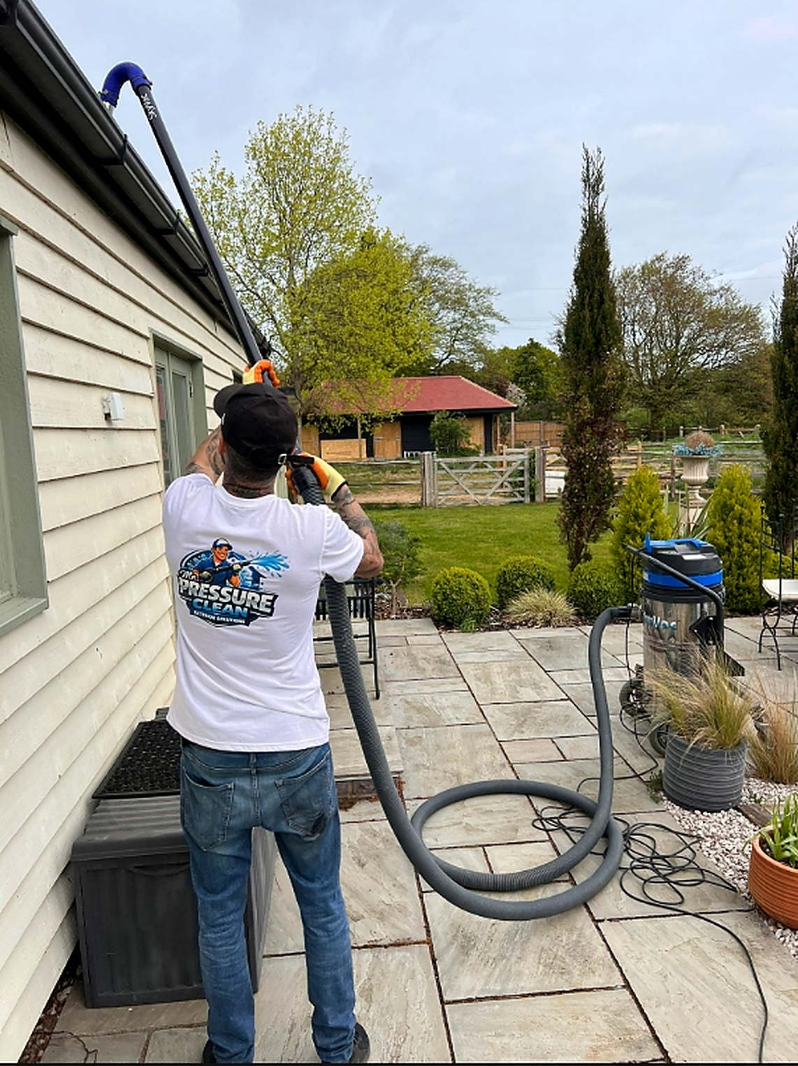 Ryan in a Mr Pressure Clean shirt vacuuming gutters at a property